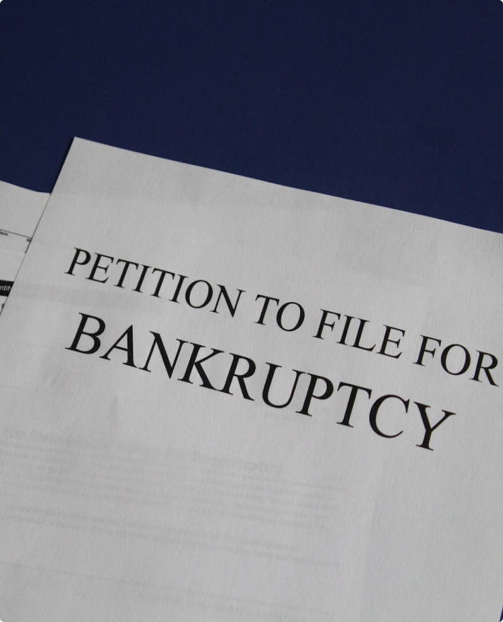 A close-up of a legal document prominently titled "PETITION TO FILE FOR BANKRUPTCY" in black serif text.